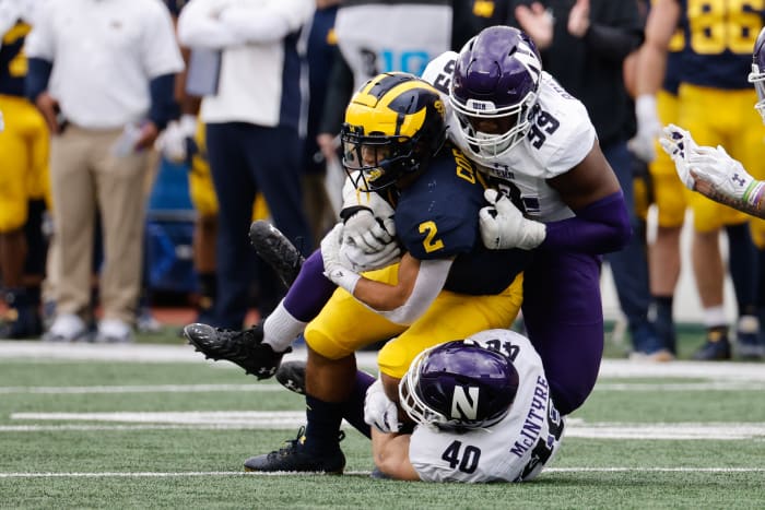 Oct 23, 2021; Ann Arbor, Michigan, USA; Michigan Wolverines running back Blake Corum (2) is tackled by Northwestern Wildcats linebacker Peter McIntyre (40) and defensive lineman Adetomiwa Adebawore (99) in the first half at Michigan Stadium. Mandatory Credit: Rick Osentoski-USA TODAY Sports